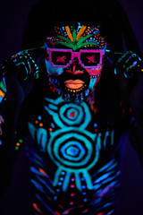 Naklejka premium portrait of fantastic disco dancer with fluorescent make-up glowing in dark isolated space. dance, dj, fluorescent luminescence concept