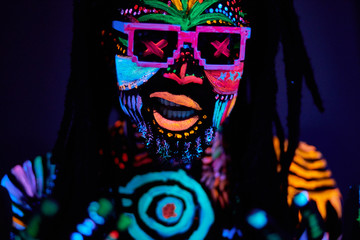 close-up portrait of african dj dancer with luminescent make-up and dreadlocks, wearing sunglasses....