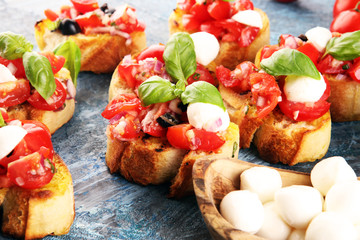 Traditional italian bruschetta with cherry tomatoes, cream cheese, basil leaves on rustic background. Italian antipasti mediterranean food