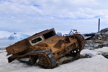 Rusty tank wreck in Antarctica, at Stonington Island east base with glacier in background