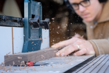 Close up of man using wood router tool with sawdust flying