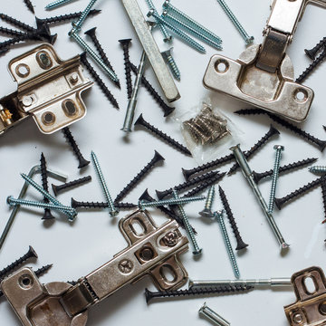 bisagras, tornillos de diferentes tipos, sobre un fondo azul cielo 