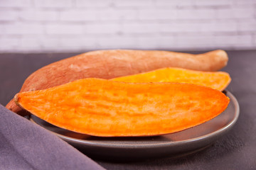 Raw sweet potatoes on the black table.