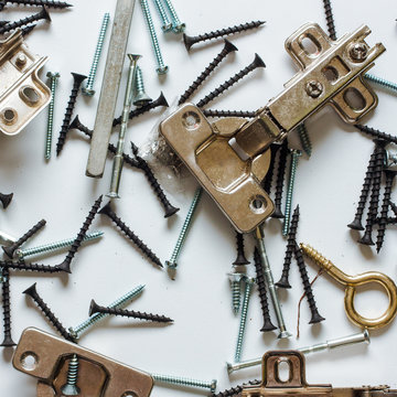 bisagras, tornillos de diferentes tipos, sobre un fondo azul cielo 