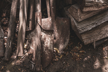 Old shovel in the ground. Farmhouse tools and firewoods on dirty ground. Rustic textures