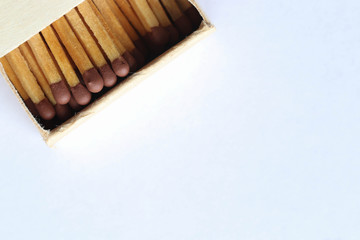 Macro photo of an open matchbox with wooden matches on a light blue background.