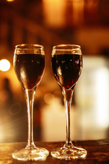 Two glasses of alcoholic drink on a wooden table. Warm tint