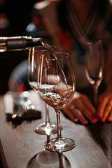The waiter pours wine into a glass in a restaurant. Close-up, natural light . Shallow depth of field