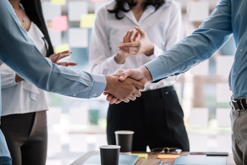 Teamwork of business people at meeting shaking hands to seal a deal with his partner.