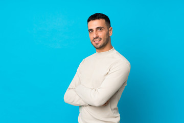Young man over isolated blue background with arms crossed and looking forward