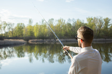A man fishing in a business suit, in a white shirt and tie
