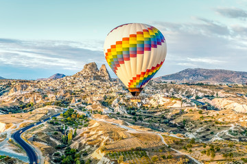 Bright single hot air balloon drifts across highways and dwarfing old town