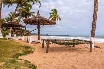 Axim beach with coconut palm trees and sunbeds lying on the gold coast of Ghana West Africa.