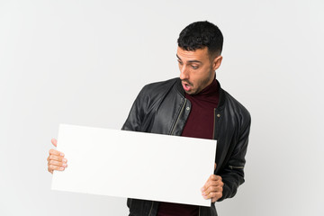 Young man over isolated white background holding an empty white placard for insert a concept