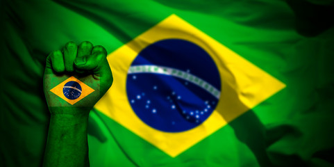 Banner of Flag of Brazil painted on male fist, fist flag, country of Brazil, strength, power, concept of conflict. On a blurred background.