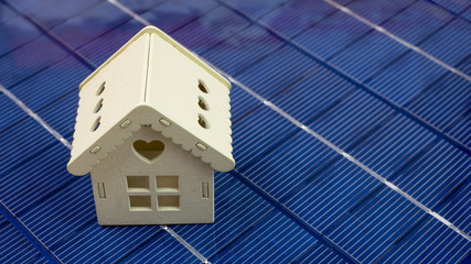 closeup of wooden house model on photovoltaic panel, concept of ecology and green energy, panorama