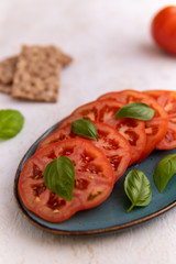 Fototapeta na wymiar sliced tomatoes and basil on blue plate 