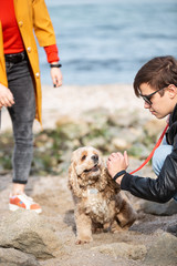 Young man training a dog at the sea shore to make it obedient.