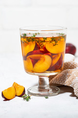 black tea with plum and thyme on white background, vertical closeup
