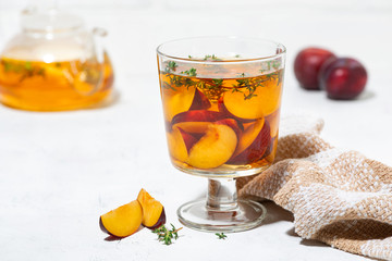 black tea with plum and thyme on white background, closeup