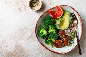Vegan tempeh buddha bowl. Marinated tempeh in smoky bbq sauce marinade or teryaki tempeh with rice, steamed broccoli, avocado, blood orange and micro greens.