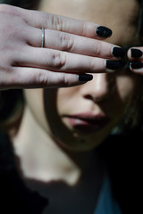 Young woman hiding her eyes with the hands. Not wanting to see or not wanting to be seen. Focus on the hands.