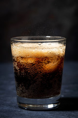Coca Cola with ice in a glass on a dark background