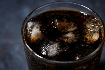 glass of coca cola with ice on a black background, top view closeup