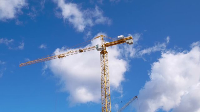 A construction crane on a blue sky with Cumulus clouds. Timelapse. Construction site.