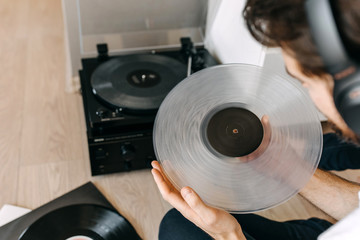 Close-up of male hands putting a transparent vinyl record on a vinyl player.