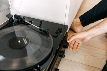 Close-up of male hands putting a transparent vinyl record on a vinyl player.