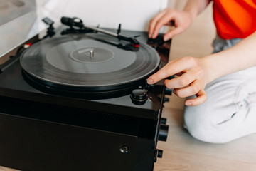Close-up of female hands putting a transparent vinyl record on a vinyl player.