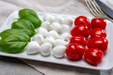Italian food served as flag of Italy Tricolore with fresh fresh green basil, white mini mozzarella cheese and red cherry tomatoes