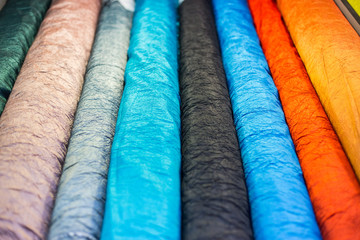 Rows of plain colored fabric with a ruffled texture on display in a sewing store.