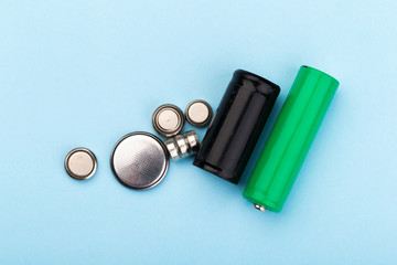 many new and used batteries of different shapes, AA, round batteries on a blue background.
