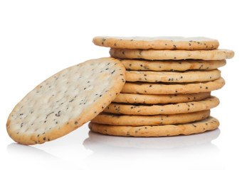 Stack of round organic crispy wheat and five grain salty crackers with seeds on white.