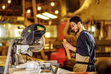 caucasian carpenter preparing wooden furniture for customers, work on an order, use electric machine for sawing and cutting, handicraft, carpentry concept