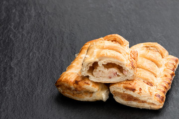 Cheese and bacon sausage rolls on black stone background