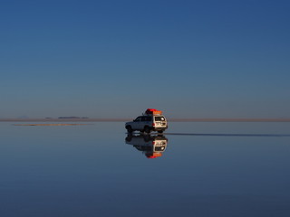 Fototapeta premium Car in the world's largest salt flat, Uyuni Salt Flat, Salar de Uyuni, Bolivia. Copy space for text