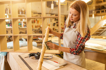 portrait of beautiful caucasian woman carpenter dealing with handicraft, woman has own business connected with making wooden furniture in workshop