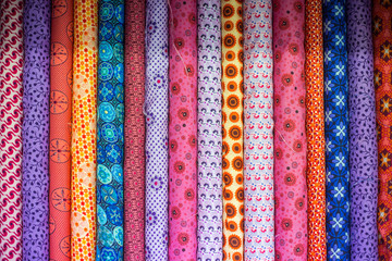 Colorful African inspired fabrics lined up in a sewing shop, to be used for clothing or DIY decoration.