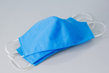 Blue medical masks on a white table handmade. Mask shortages during quarantine