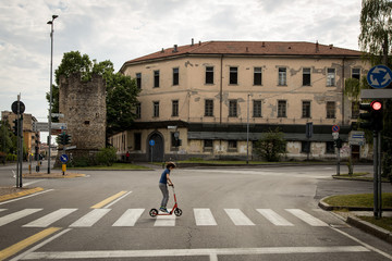 Obraz premium Bambino attraversa città deserta col monopattino, Bergamo