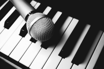 Microphone lying on the piano keyboards. Free time activities at home. Karaoke hobby. Creating music.