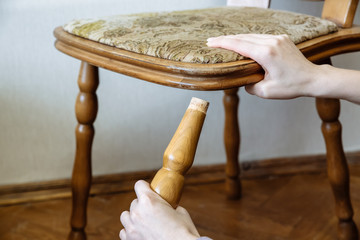 Broken chair. Woman is holding it in hands. Old furniture.