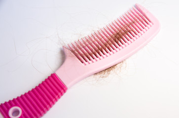 Hair loss problem. Pink comb on white background.