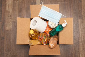 Donation goods in carton box close up photo. Pasta, toilet paper, medical mask, sunflower oil, sanitizer, caned food, bread. Stay home. Food delivery for those who need.
