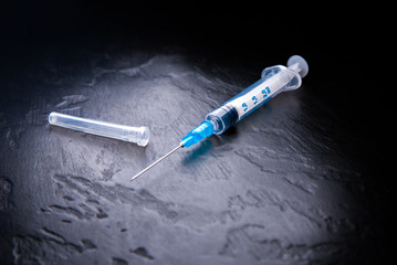 Syringe with needle on black background. Vaccination from virus. Injection for medical treatment.