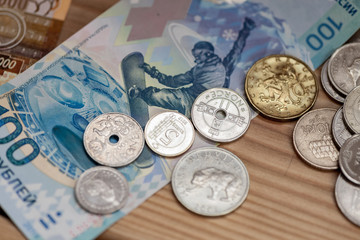 Banknotes ans coins laying on a wooden table surface