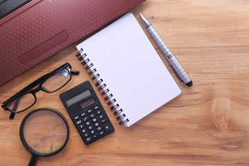  notepad , pen , calculator,laptop and pen on table 